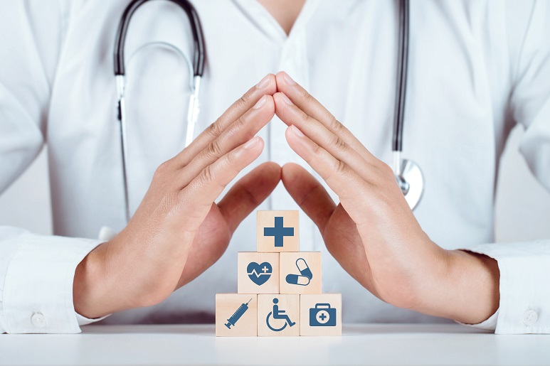 Pyramide de cube en bois avec symbole de soins couverts par les mains jointes d'un médecin